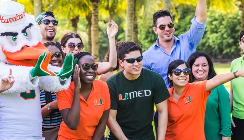 Group of young people wearing green and orange t-shirts next to a person dressed as a chicken