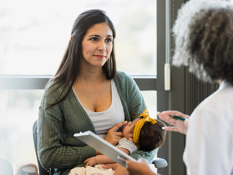 woman with baby in her arms in consultation with a doctor