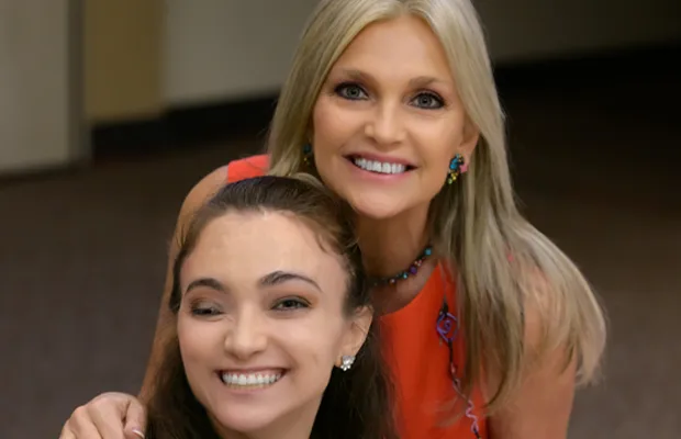 blonde and black-haired woman hugging each other