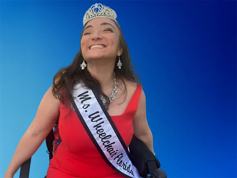 Woman in red dress wearing silver crown in front of blue background