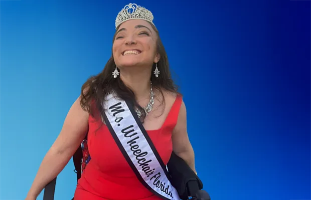 Woman in red dress wearing silver crown in front of blue background