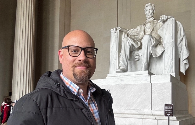 A man smiling next to the statue of Abraham Lincoln