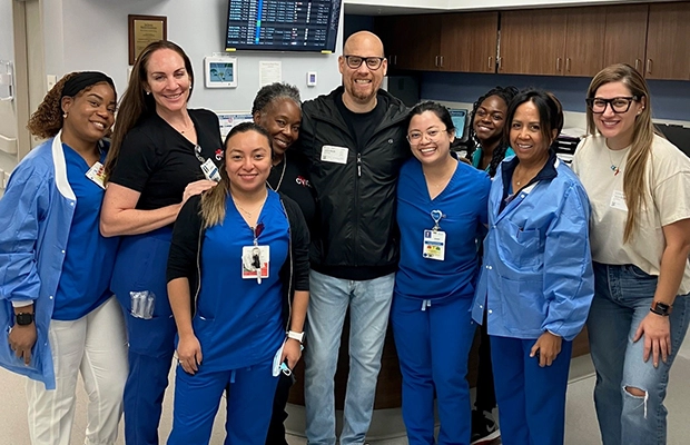 A group of nurses smiling next to a man