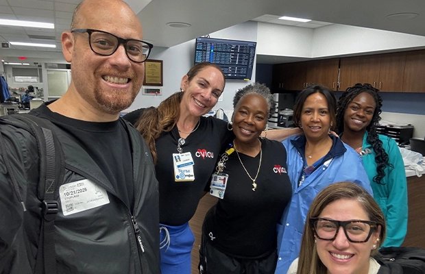 A group of nurses smiling next to a man