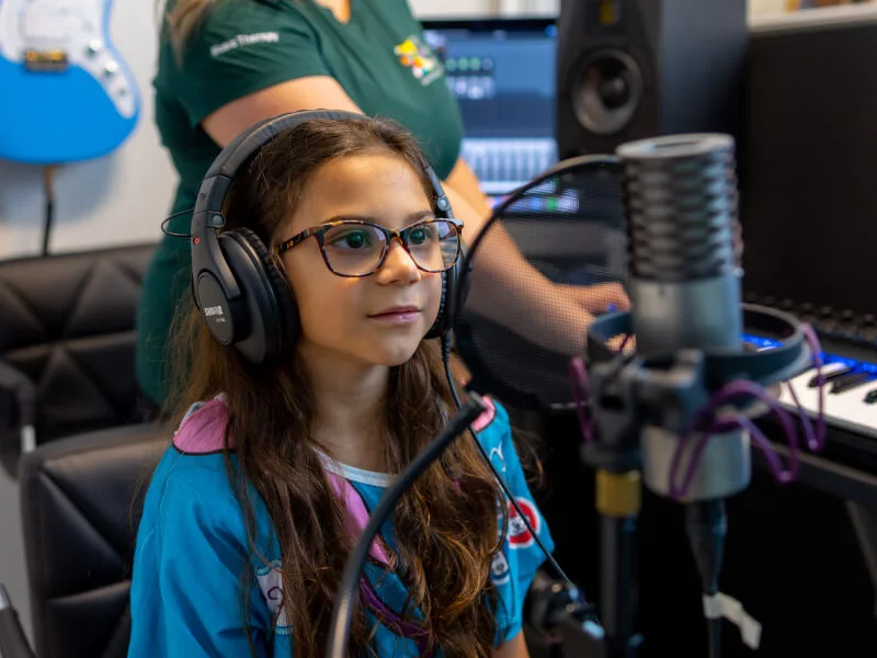 A young girl in a booth using a microphone