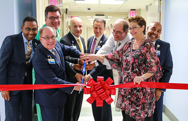 Hospital staff cutting a red ribbon in front of the new suites