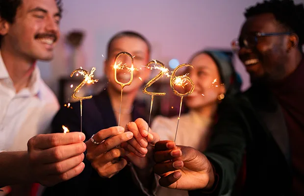 A group of people holding sparklers, the sparklers read out 2026