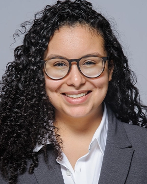 Close-up of a woman with curly hair wearing a black t-shirt, smiling at the camera.