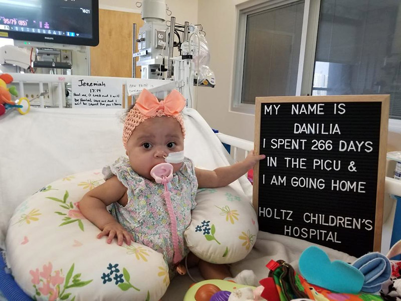 A baby on a medical bed sitting next to a sign