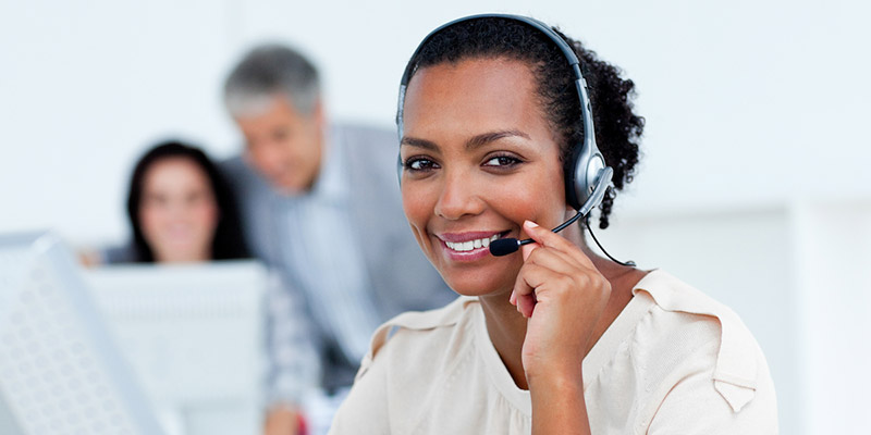 A woman speaking into a headset, she smiles at the camera