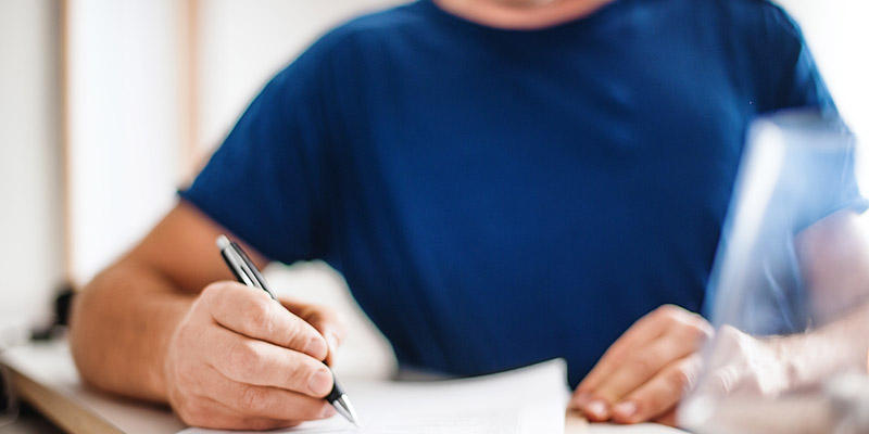 A closeup of a person writing on a piece of paper
