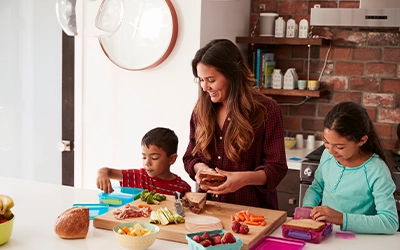 Photograph of a mother cooking alongside her two children.