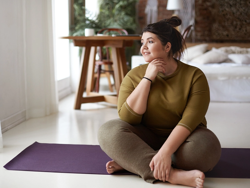 photograph of woman sitting in the living room of her house looking at the horizon