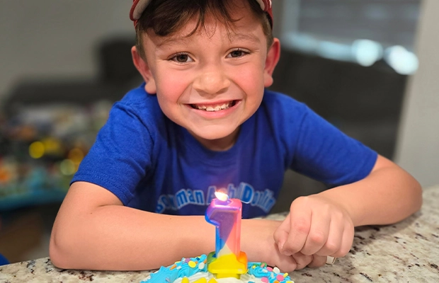 smiling boy in front of his birthday cake