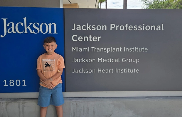 Child posing next to Jackson Health sign