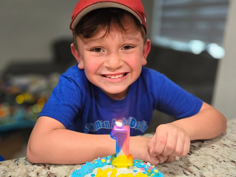 smiling boy in front of his birthday cake