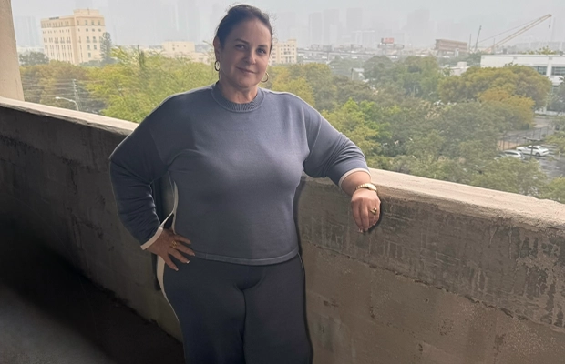 A woman posing and smiling at the camera from a balcony