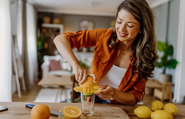A woman making orange juice while smiling
