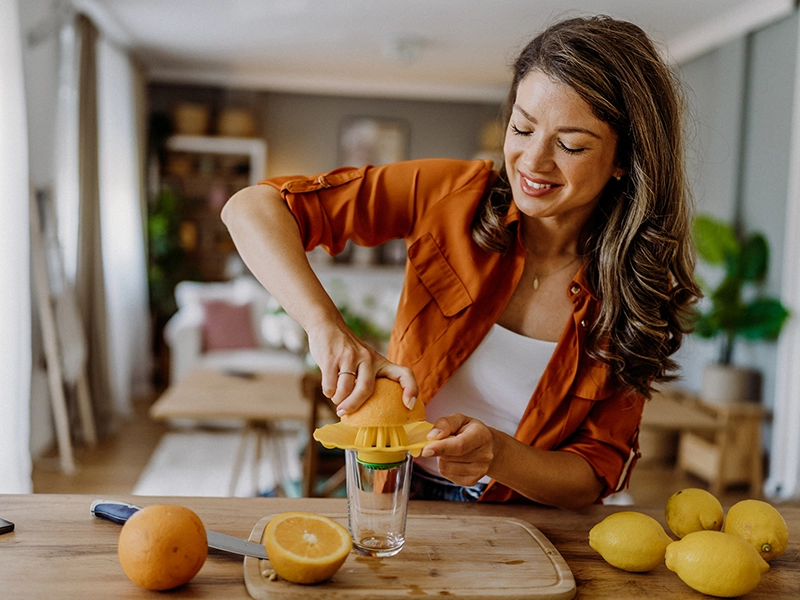 A woman making orange juice while smiling