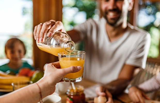 A man serving orange juice during a family gathering