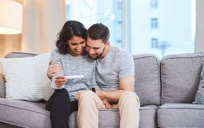 couple watching pregnancy test while smiling