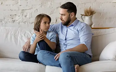 A father and son sitting on a couch and having a discussion