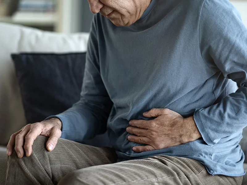 Close-up of a man massaging his stomach as if he were in severe pain.