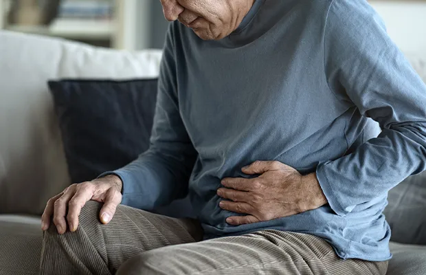 Close-up of a man massaging his stomach as if he were in severe pain.