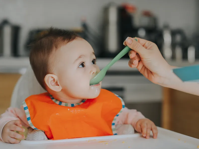 baby in orange t-shirt eating