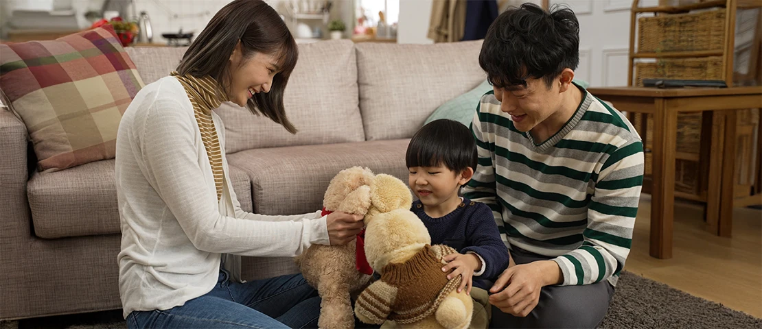 Two parents paying with a child and stuffed toys