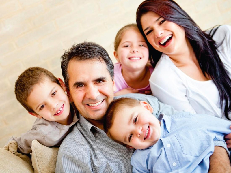 two parents and their three kids smiling toward the camera.