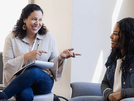 A woman and young adult speaking within an office