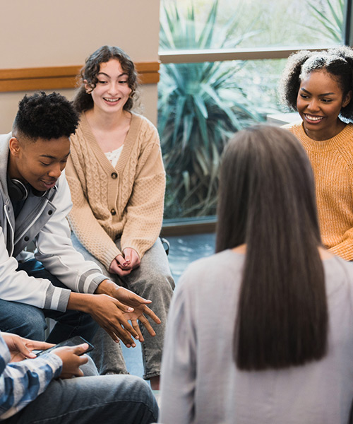A group of young adults sitting in a circle and having conversations
