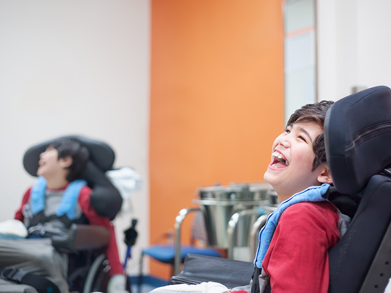 Smiling disabled little boy sitting in wheelchair at a doctor's office