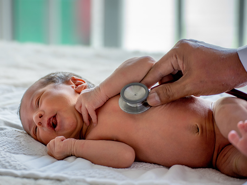 Closeup of a physician using a stethoscope on a newborn baby