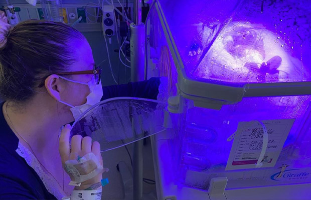 Mom watching baby inside an incubator with the light on