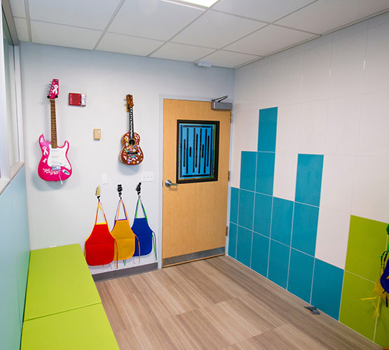 An empty room with guitars on the wall, a green seating area, and blue and green colored walls