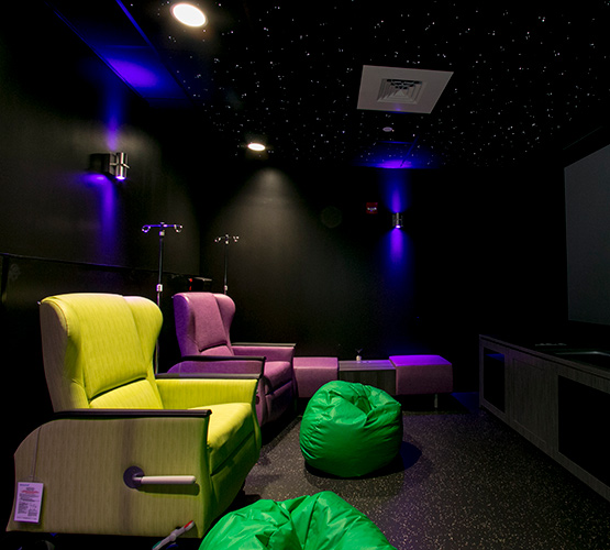 Dark room with two bright chairs, bean bags and a large television screen