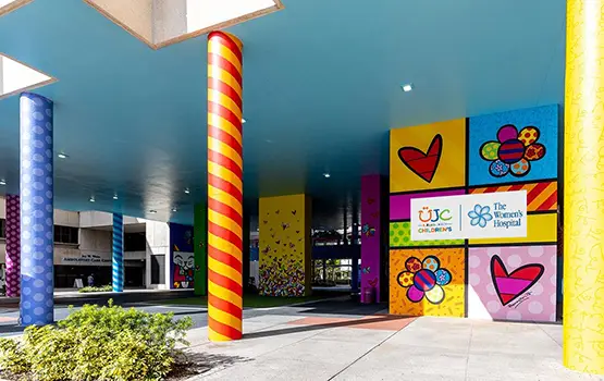 Exterior image of a building, there are colorful murals throughout