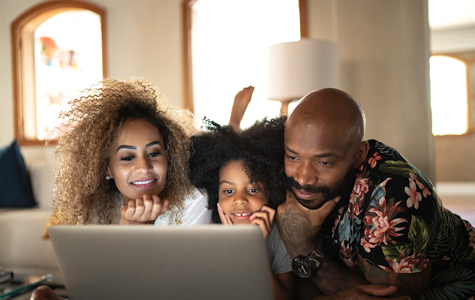 A family of three laying down and looking at a computer screen