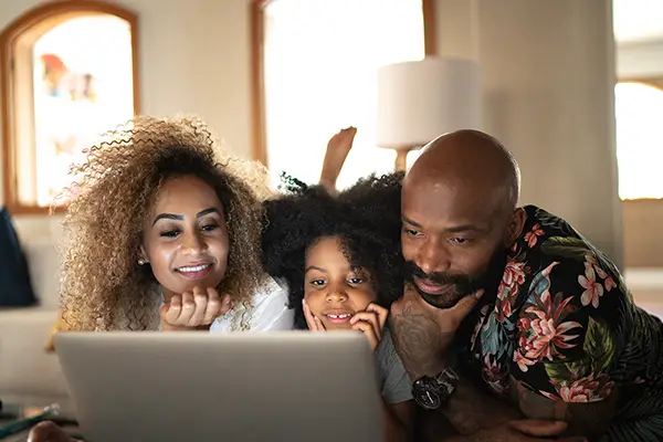 A family of three laying down and looking at a computer screen