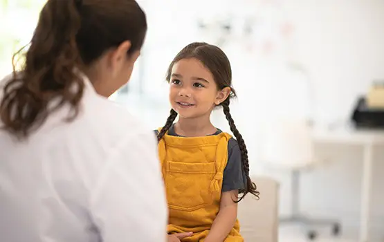 A young girl smiling at a medical professional, she's in a medical setting
