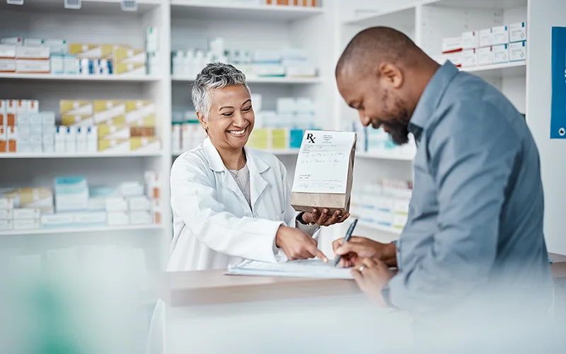 A pharmacist smiling as a client signs a document
