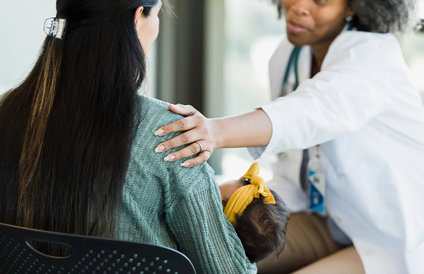 An image showing a doctor speaking with a woman holding her baby.