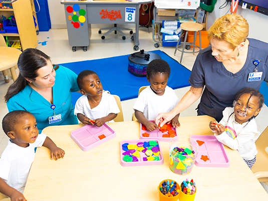 Children having a snack with a nurse and teacher