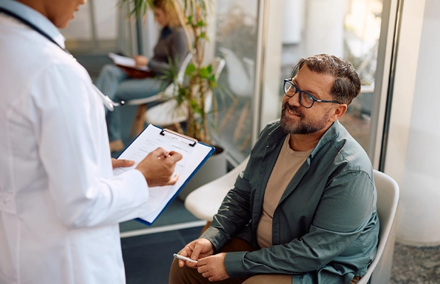 Man in a green blazer sitting in a doctor's office while talking to his doctor