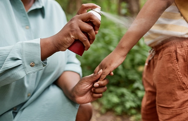 man applying repellent to child