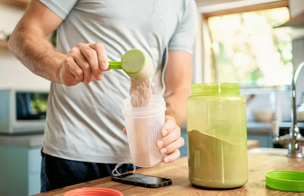 Close-up of a person in the kitchen pouring protein into a container