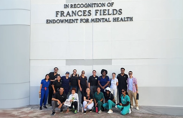 group of doctors posing and smiling at the camera under a sign that says IN RECOGNITION OF FRANCES FIELDS ENDOWMENT FOR MENTAL HEALTH