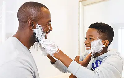 boy next to his father shaving